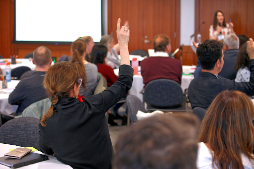 An attendee raises their hand at the Living Together Symposium in 2025.