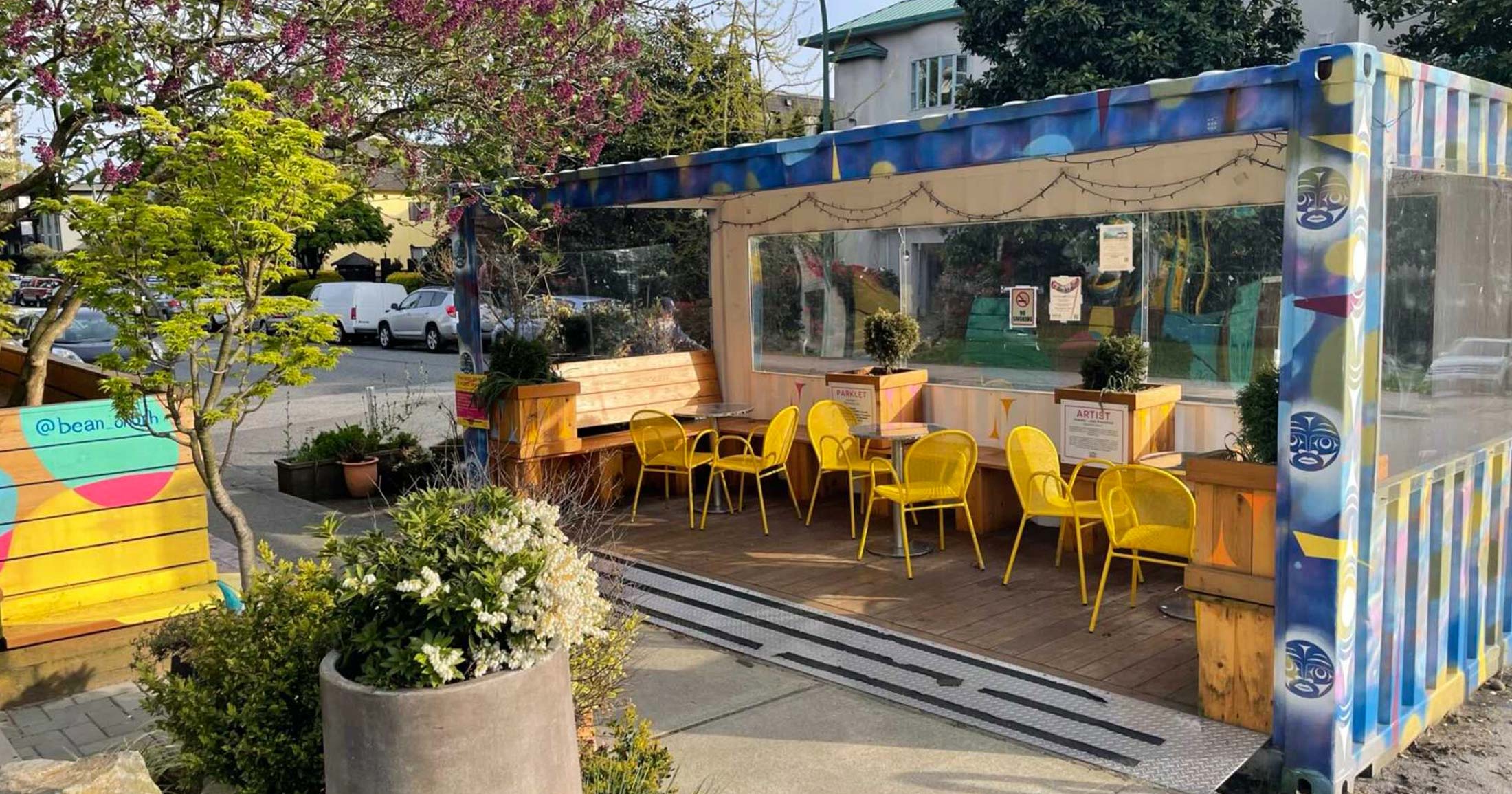 A parklet in front of Quayside Cohousing featuring a converted and painted shipping container with outdoor seating and plants.