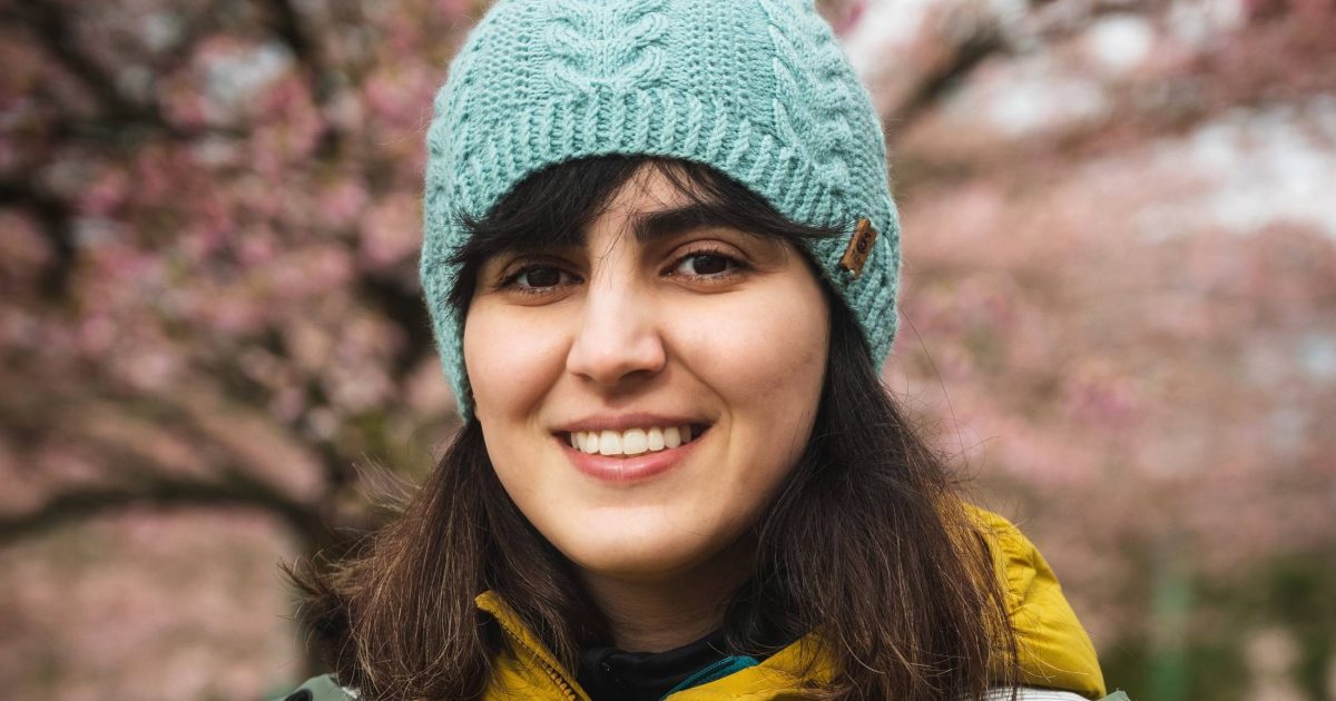 Sara Emami looks at the camera wearing a blue knit toque and yellow jacket.