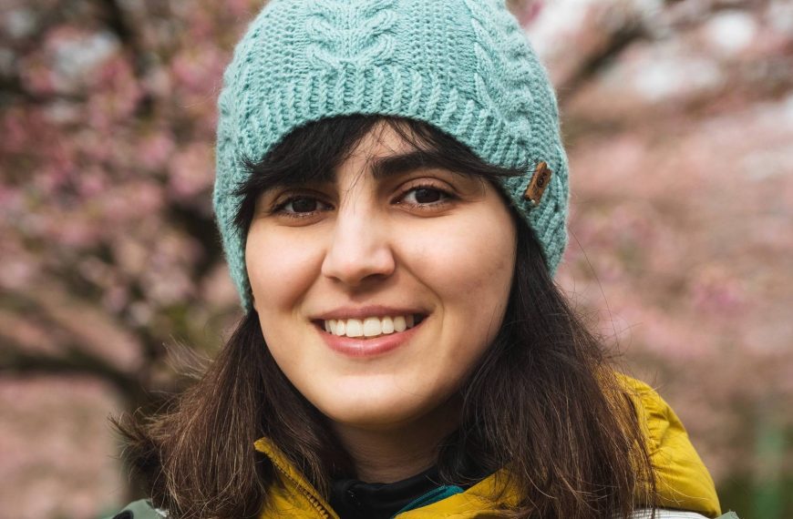 Sara Emami looks at the camera wearing a blue knit toque and yellow jacket.
