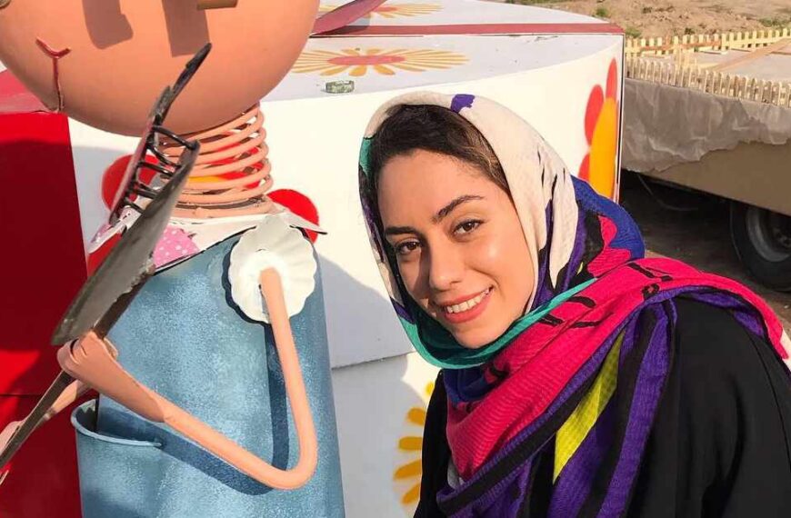 A close-up of Niloofar wearing a colourful headscarf as she paints a sculpture in Mashhad, Iran.