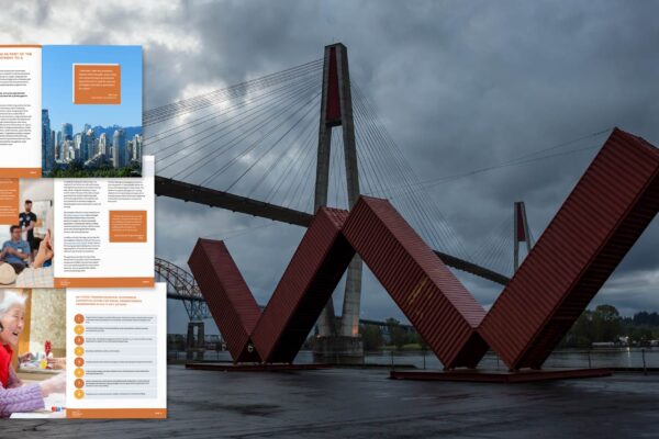 Some spreads from a practice guide float in the foreground with a bridge and public art from New Westminster in the background on a dark cloudy morning.